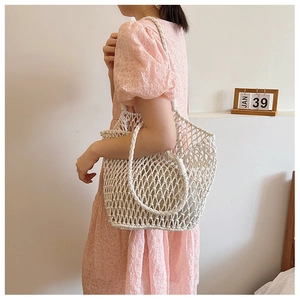 Lifestyle shot of a white hand-woven crochet mesh tote bag styled with a lace dress