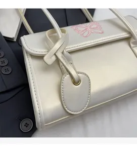 Detail shot of pearl white PU leather handbag featuring pink butterfly embroidery