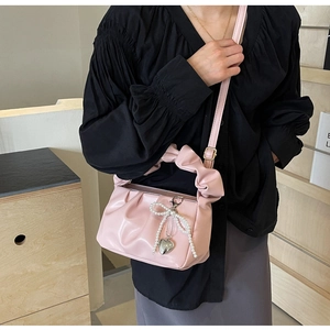 Detail of pink pleated cloud bag with pearl bow decoration and metal heart charm detail