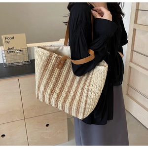 Close-up of the vertical striped straw weaving and leather handles on this tote bag