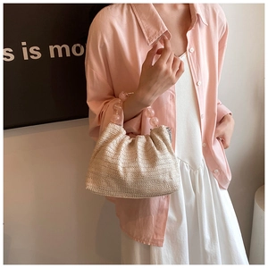 Détail du sac tressé en paille avec pli en forme de nuage et poignée en perles roses