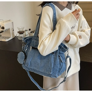 Detail view of denim tote bag featuring functional front zipper pockets and round coin purse