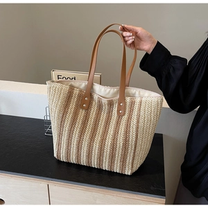 Close-up of woven straw tote bag with brown leather handles and striped texture