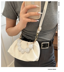 Detail of trendy off-white cloud bag with large transparent resin bead handle and gold hardware
