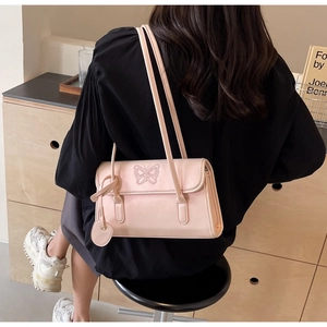 Detail of light pink shoulder bag with butterfly embroidery and heart pendant charm