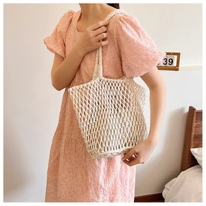 Detail of hand-woven cream tote bag showing thick cotton rope mesh and inner fabric lining