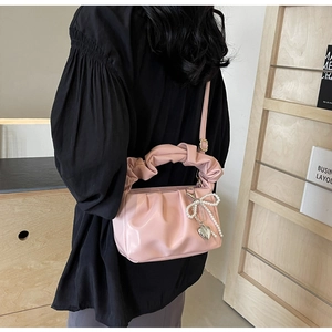 Detail of pink pleated PU handbag with pearl bow and heart charm on a model