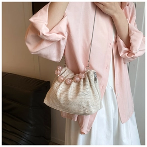 Détail d'un sac bandoulière en paille avec perles acryliques roses et chaîne en métal