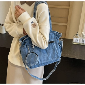 Detail of blue washed denim tote bag with functional pockets and mini coin purse accessory