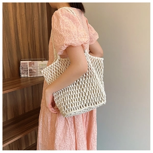 Detailed macro view of white hand-woven cotton rope handbag with hollow mesh pattern texture