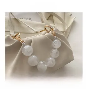 Close-up of cream pleated cloud bag with marble resin chain and gold hardware
