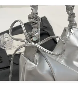 Detailed macro view of silver metallic PU handbag with bow accent and pleated handle