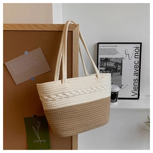 Fashionable woven tote bag in cream and beige two-tone design hanging on cork board