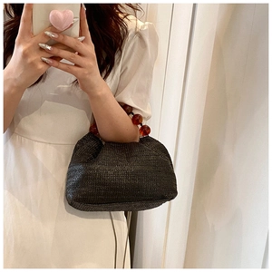 Détail du sac à main en paille noire avec poignée élégante en perles ambre pour l'été