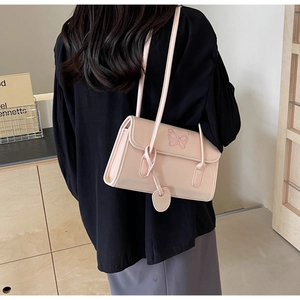 Detail of light pink PU leather bag with butterfly embroidery shown on model shoulder
