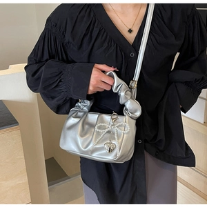 Detail view of silver pleated PU crossbody bag with pearl bow and heart metal charms