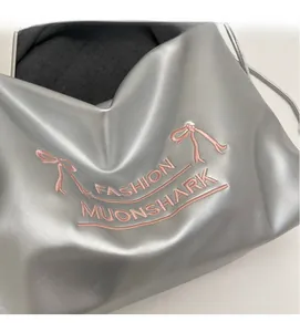Detail of silver metallic PU handbag featuring pink bow embroidery and fashion text
