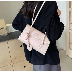 Detail of light pink PU shoulder bag featuring butterfly embroidery and heart charm