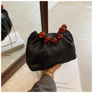 Détail du sac nuage noir en paille avec de grandes perles en résine ambre sur le bord