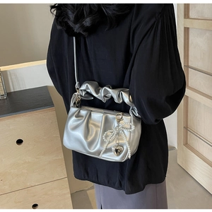 Detail of silver ruched PU handbag featuring pearl bow and metallic heart charm