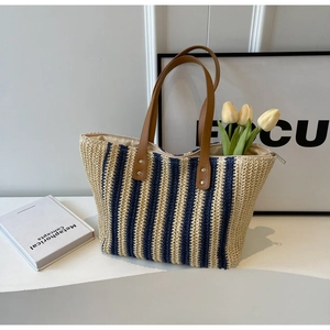 Minimalist straw tote bag with navy blue stripes and brown leather handles for women