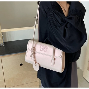 Detail of light pink PU leather shoulder bag with butterfly embroidery and heart charm