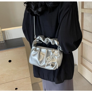 Close-up of silver PU leather bag featuring pearl bow and heart charms on a model