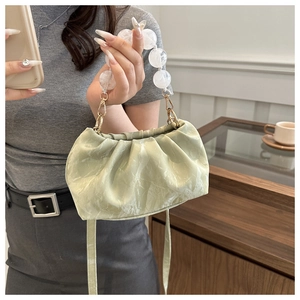 Detail of light green pleated cloud bag with clear beaded handle and gold hardware