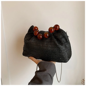 Détail du sac nuage noir en paille avec poignée en perles d'ambre et chaîne en métal