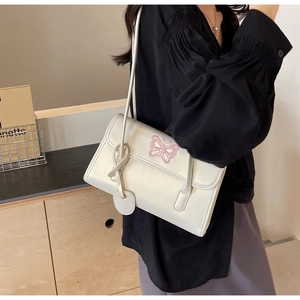 Close-up of white PU shoulder bag featuring delicate pink butterfly embroidery and sleek straps