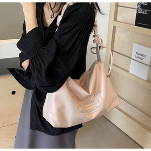 Close-up of soft pleated cloud strap and bow embroidery on apricot PU shoulder bag