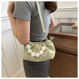 Side view of mint green cloud bag with marble bead handle and golden hardware