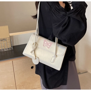 Detail of white PU shoulder bag featuring delicate pink butterfly embroidery and textures