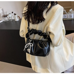 Detail of black ruched shoulder bag with pearl bow and silver heart pendant