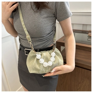 Detail of light green pleated cloud bag with large white bead strap and shoulder strap