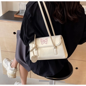 Close-up of cream white PU leather handbag featuring delicate pink butterfly embroidery