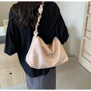Detail of a light pink hobo shoulder bag featuring ruffled straps and MOONSHARK graphic print