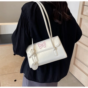 Detail of white PU shoulder bag featuring pink butterfly embroidery and a heart-shaped charm
