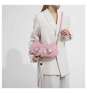 Chic pink crescent shoulder bag in glossy PU leather worn with a beige blazer