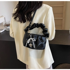 Detail of black ruched PU leather handbag with pearl bow and silver heart pendant