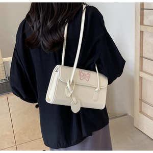 Detail of off-white PU leather shoulder bag with pink butterfly embroidery and heart charm