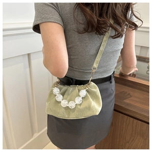 Detail of light green pleated cloud bag featuring chunky white marble bead handle