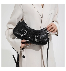 Detailed view of black crescent shoulder bag featuring glossy pleated leather and silver buckles