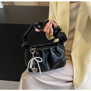 Detail of black PU cloud bag with pleated handle and pearl bow pendant decoration