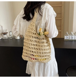 Detail view of woven straw shoulder bag featuring large mesh pattern on a white dress model