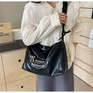 Detail showing the white bow print and branding on the black PU leather tote bag