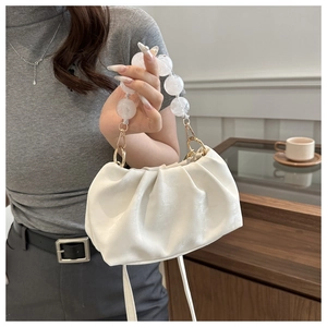 Detail of white pleated handbag featuring frosted bead handle and gold metal hardware
