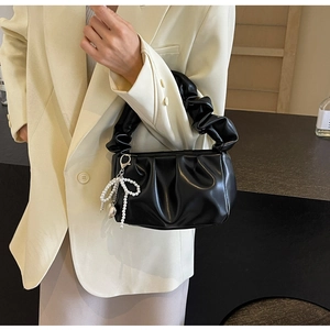 Close-up of black PU leather cloud bag with ruched handle and pearl bow charm