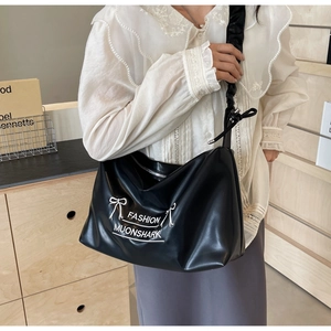 Detailed view of black PU tote bag with ribbon decoration and wide pleated strap