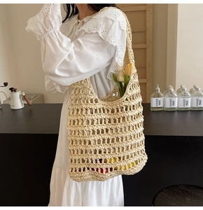 Detail of a handmade cream-white woven straw tote bag featuring a hollow mesh design